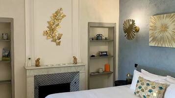 A bedroom with a bed, a fireplace, a shelf with books, and decorative wall art.
