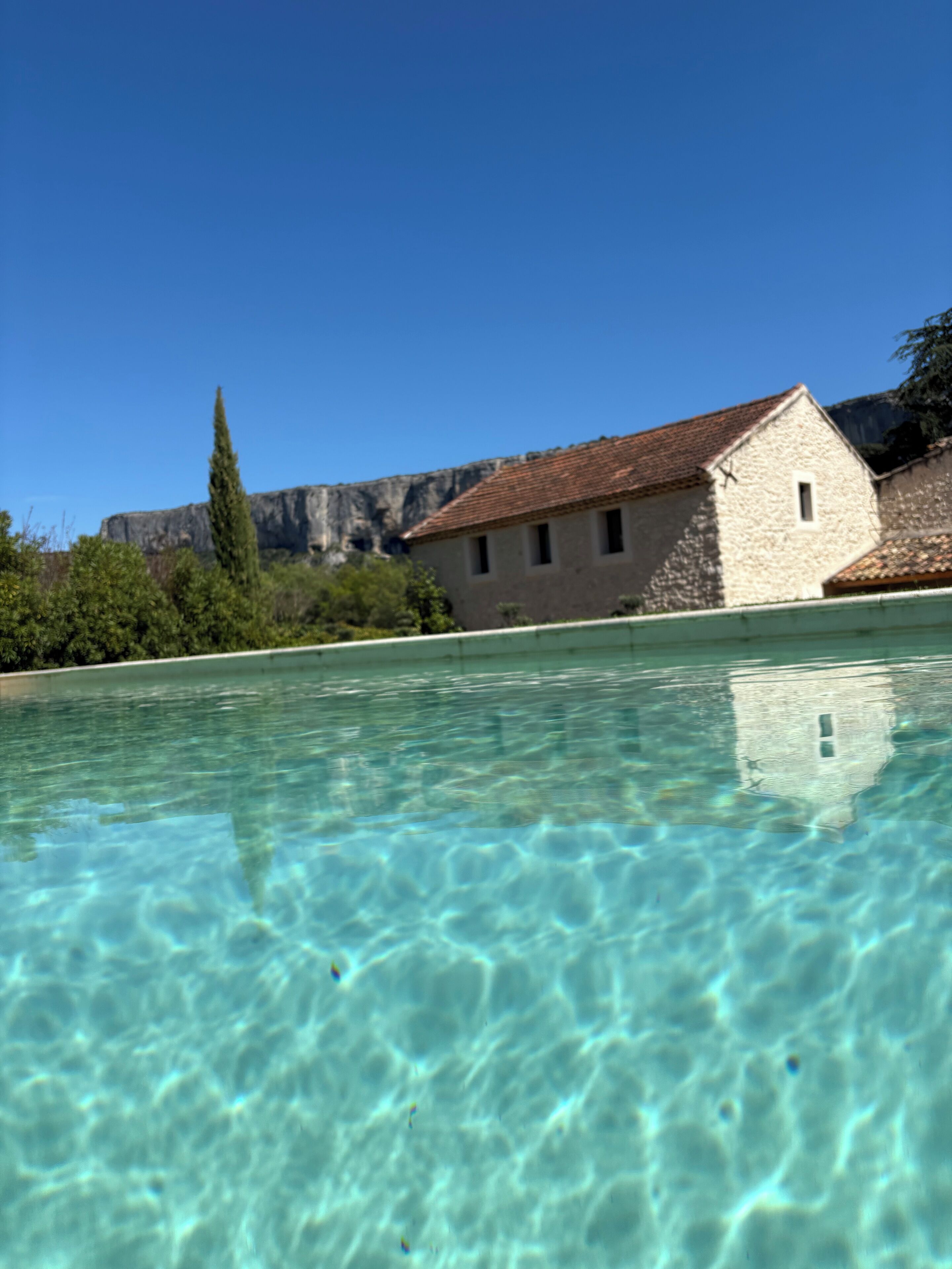 A clear pool with a stone building in the background.