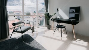 Une chambre moderne avec une grande fenêtre, un bureau, une chaise et une plante en pot.