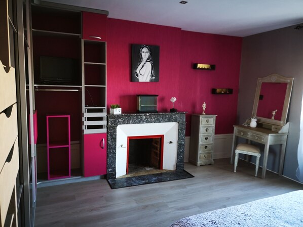 Una habitación con chimenea, un escritorio, un aparador, un espejo y un cuadro en la pared.