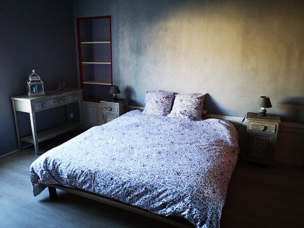 Un dormitorio con una cama, dos mesitas de noche, un aparador y una escalera apoyada en la pared.