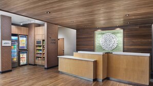 Ein Hotel-Rezeptionsbereich mit einem hölzernen Empfangsschalter, einer Minibar und einem Selbstbedienungsgetränkeautomaten.