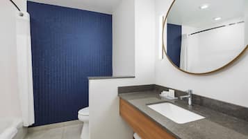Een moderne badkamer met een wit wastafelmeubel, een spiegel en een douchegordijn.