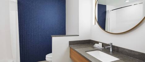 A modern bathroom with a white sink, a mirror, and a shower curtain.