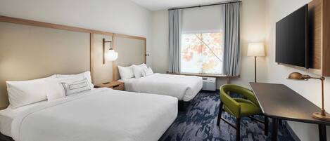 A hotel room with two beds, a desk, a chair, a TV, and a window with curtains.