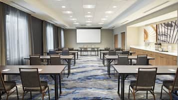 A conference room with a large screen, multiple tables, and chairs arranged for meetings.