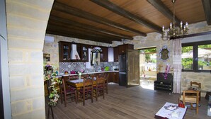 Uma cozinha ampla com piso de madeira, paredes de pedra e uma área de jantar com mobiliário de madeira.
