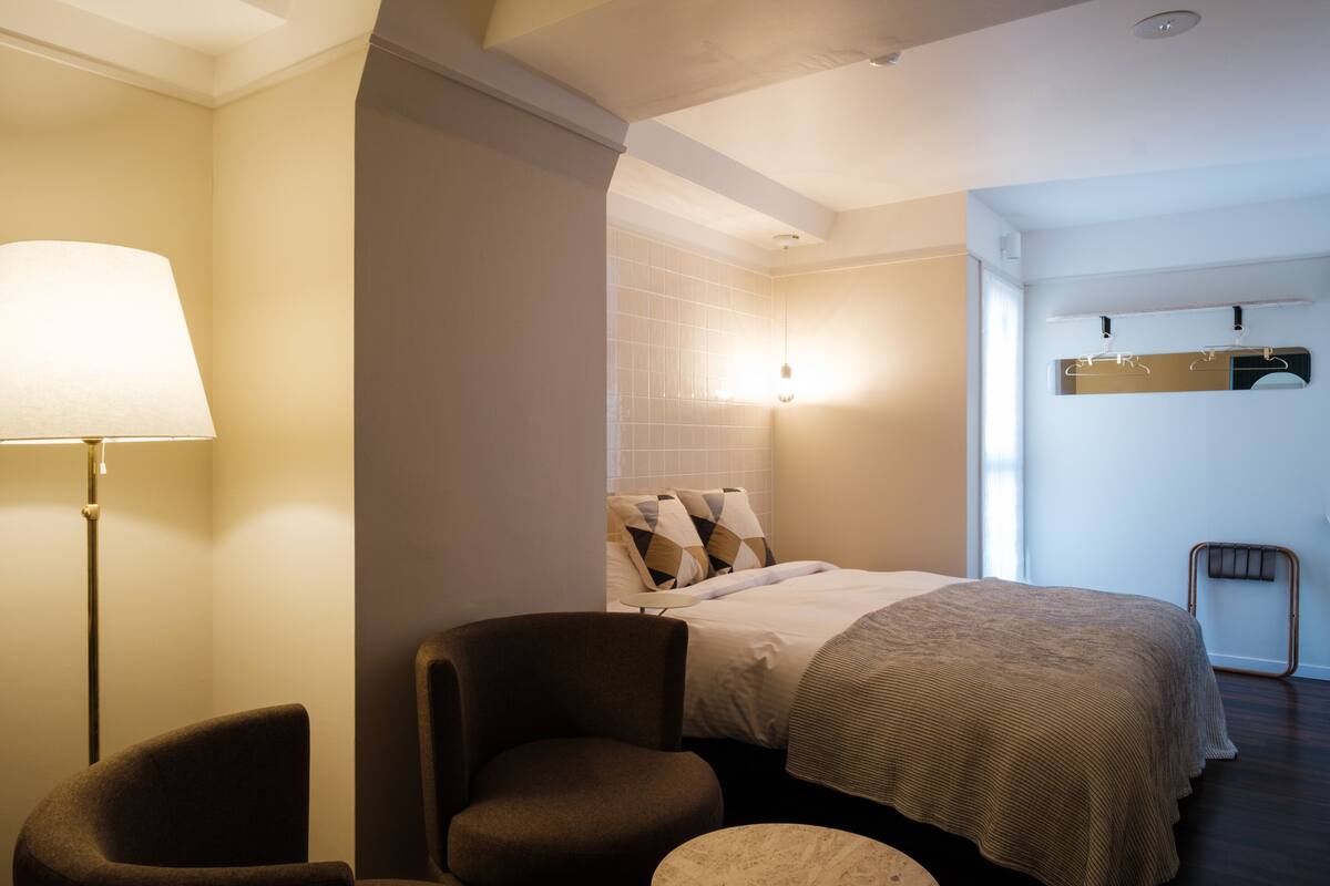 Een hotelkamer met een bed, een stoel, een lamp en een tafeltje.