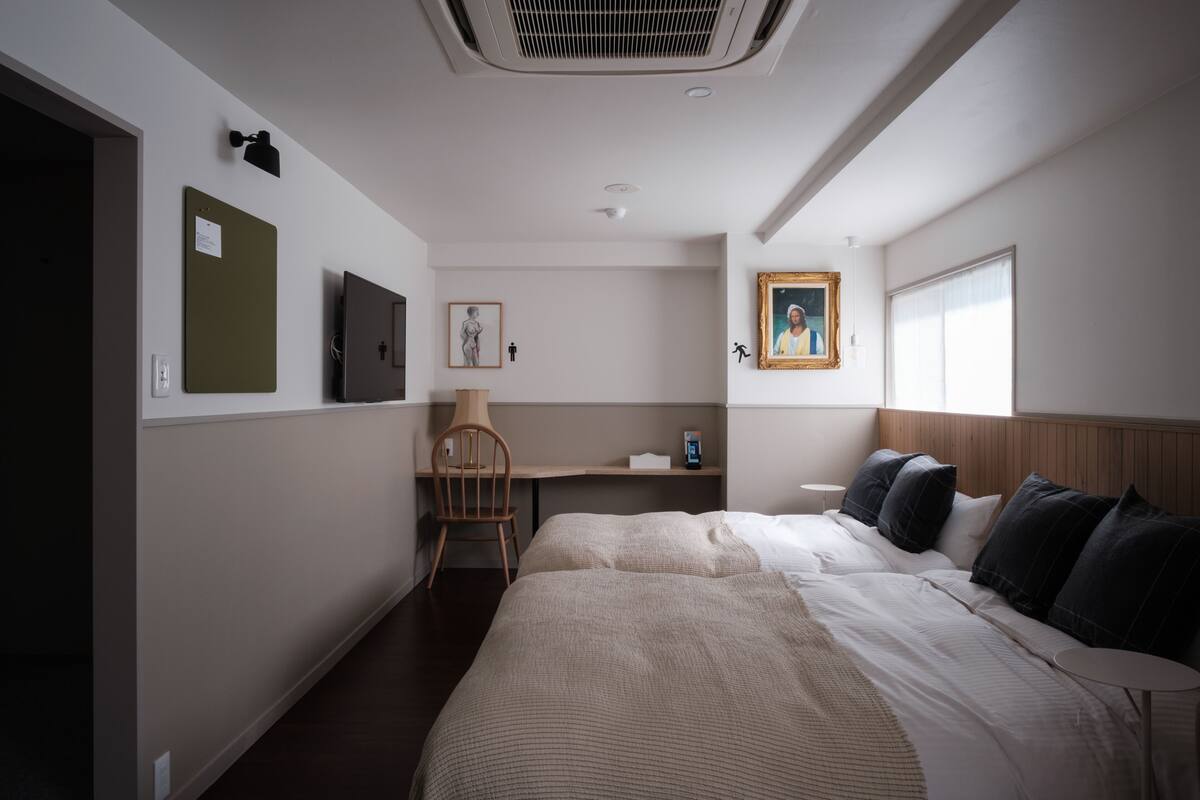 Een hotelkamer met een bed, een bureau, een stoel, een foto aan de muur en een raam.