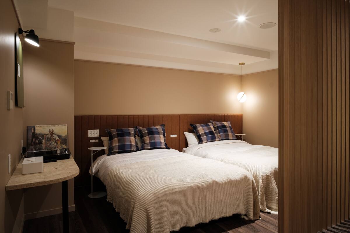 Een hotelkamer met twee bedden, een nachtkastje, een lamp en een kunstwerk aan de muur.