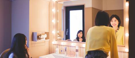 A bathroom with a vanity, mirror, and lights.