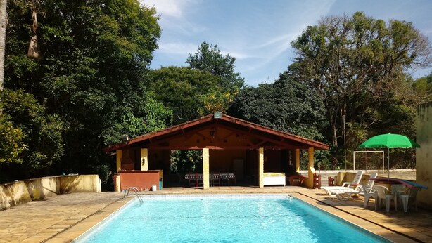 A swimming pool with a covered seating area and lounge chairs. - An excellent place for rest and relaxation surrounded by nature. (Bragança Paulista)