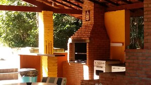 An outdoor patio with a brick oven, a table, and chairs. - An excellent place for rest and relaxation surrounded by nature. (Bragança Paulista)