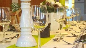 A dining table set with wine glasses, a candle, and a white vase with flowers. - Wildkräuterhotel (Windelsbach)