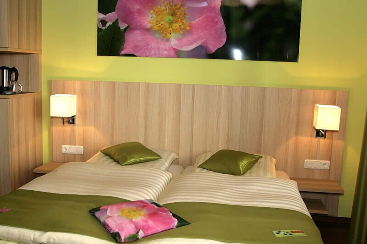 A hotel room with a bed, two bedside lamps, a nightstand, and a floral artwork on the wall.