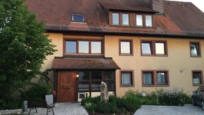 A two-story building with a brown roof, multiple windows, and a front door. - Wildkräuterhotel (Windelsbach)