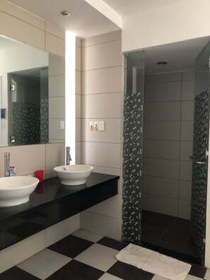 A bathroom with two sinks, a shower, and a tiled floor.
