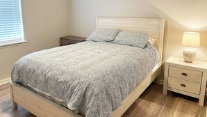 Un dormitorio con cama, mesita de noche y lámpara.