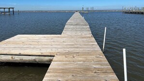 Un muelle de madera que se adentra en aguas tranquilas, bajo un cielo despejado.