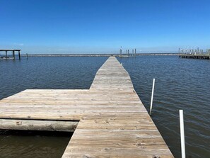 A wooden pier extending into calm water with a clear sky. - Bottoms Up  - Boat Access - Island Realty (Grand Isle)