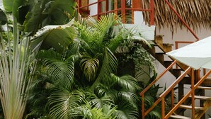 A thatched-roof building with a red railing and a staircase leading to an upper level. - Tropical Temple Siargao (General Luna)