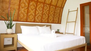 A bed with white linens, a woven headboard, a potted plant, a ladder, and a small table with a plant. - Tropical Temple Siargao (General Luna)