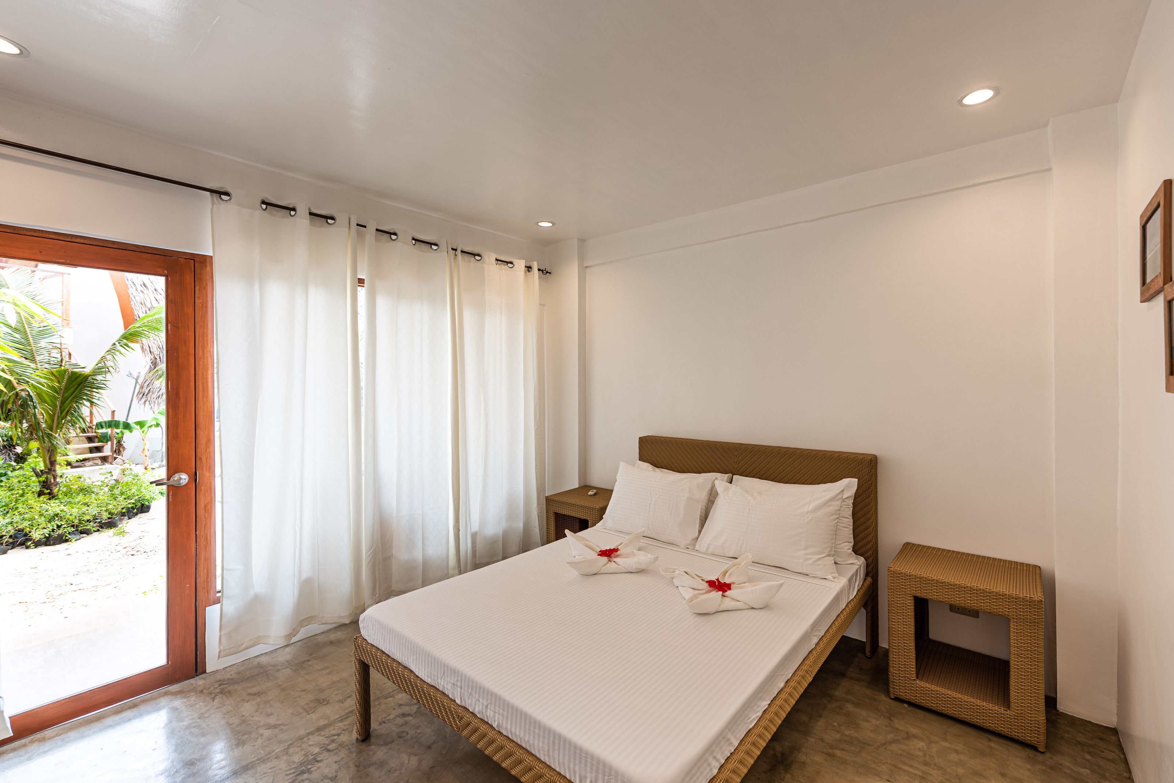Un dormitorio con cama, cortinas, una mesita de noche y acceso a un espacio exterior.
