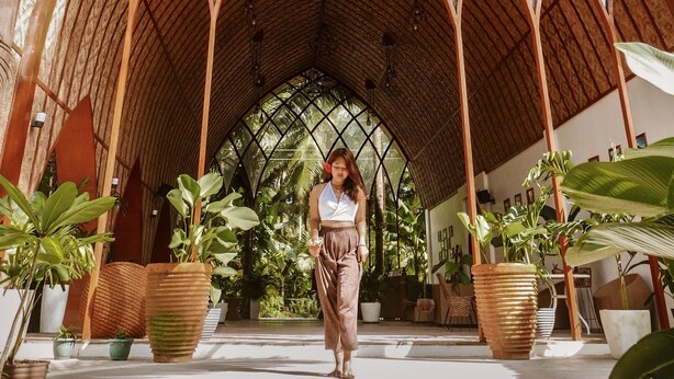 A covered outdoor area with a vaulted wooden ceiling, surrounded by potted plants and palm trees. - Tropical Temple Siargao (General Luna)
