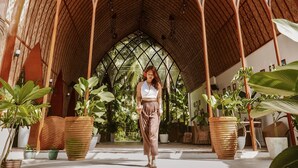 A covered outdoor area with a vaulted wooden ceiling, surrounded by potted plants and palm trees. - Tropical Temple Siargao (General Luna)