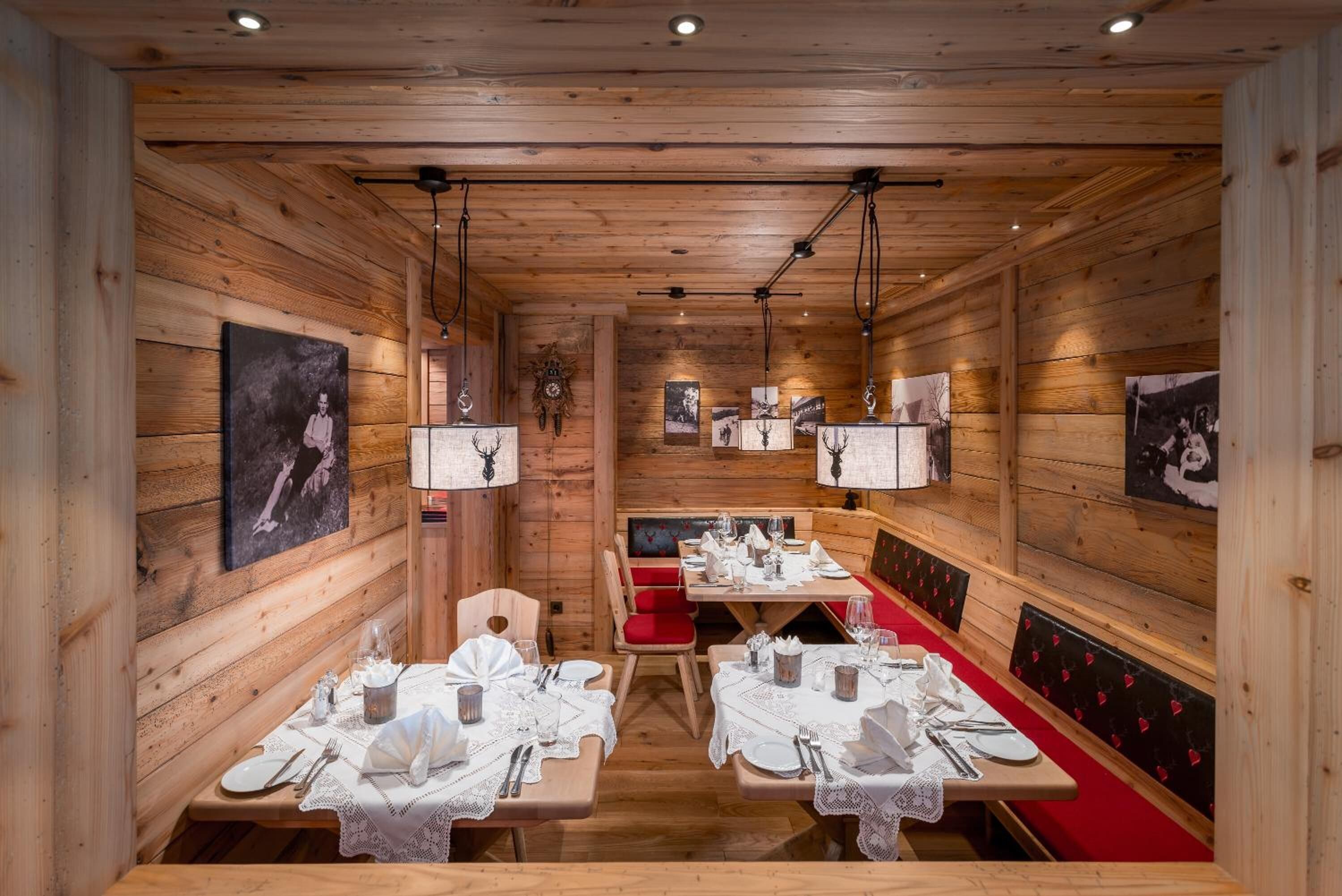 A cozy wooden interior with tables set for dining, benches, and wall-mounted artwork.
