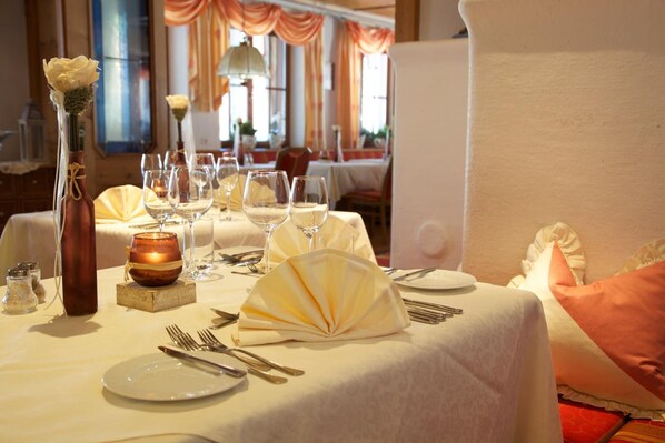 A dining table set with white tablecloths, folded napkins, and wine glasses. - Naturparkhotel Adler (Wolfach)