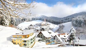 A snow-covered village with traditional buildings and a prominent church. - Naturparkhotel Adler (Wolfach)