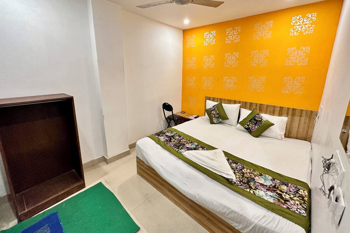Habitación de hotel con cama, escritorio, silla, ventilador de techo y pared con diseño decorativo.