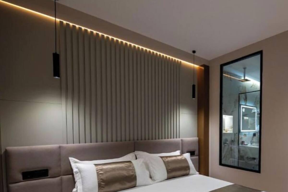 Un dormitorio moderno con una cama grande, mesitas de noche, un cabecero con listones verticales y un espejo en la pared.