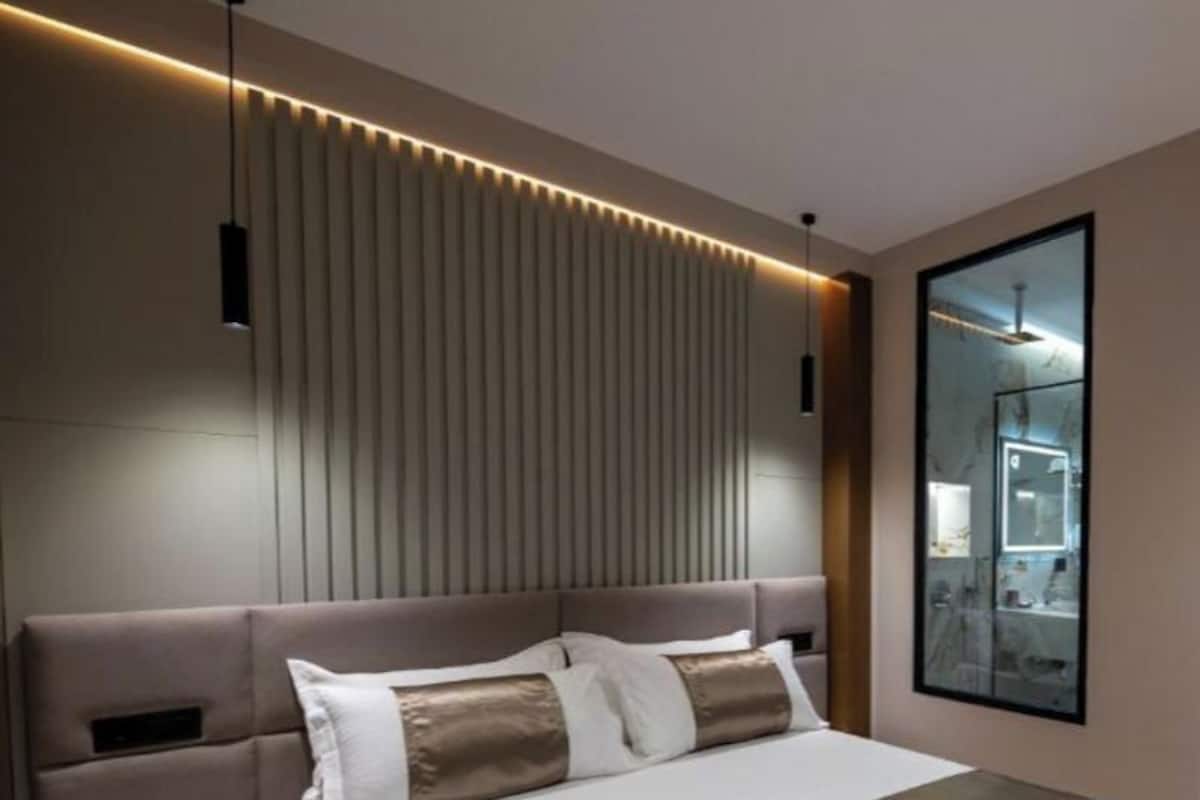 A modern bedroom with a large bed, bedside tables, a headboard with vertical slats, and a mirror on the wall.