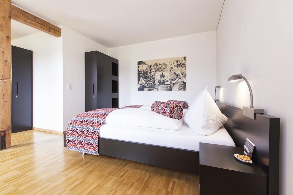 A modern bedroom with a bed, bedside table, and a wall-mounted lamp.