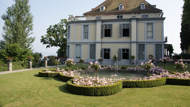 A large, two-story building with a symmetrical facade, a central courtyard with a fountain, and well-manicured gardens. - Hotel Arenenberg (Salenstein)