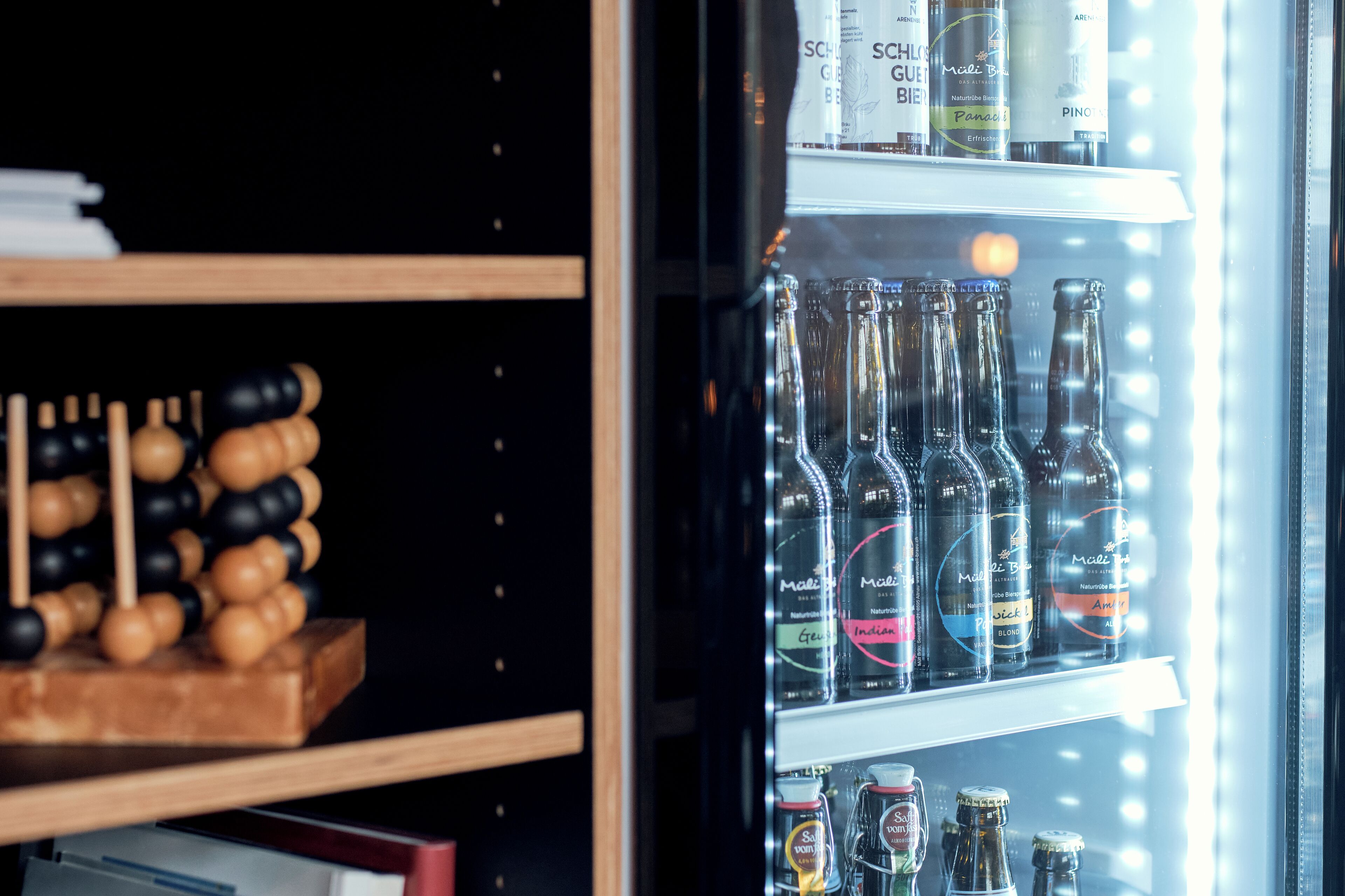 Un refrigerador lleno de varias botellas, incluyendo algunas con etiquetas como "Malibu" y "Perrier".