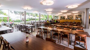 A spacious indoor dining area with multiple tables and chairs, large windows, and modern ceiling lights. - Hotel Arenenberg (Salenstein)