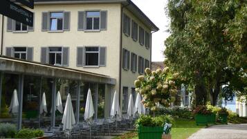 Un hotel con terraza exterior y jardín.