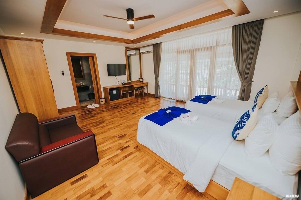 A hotel room with a large bed, a desk, a chair, and a television.
