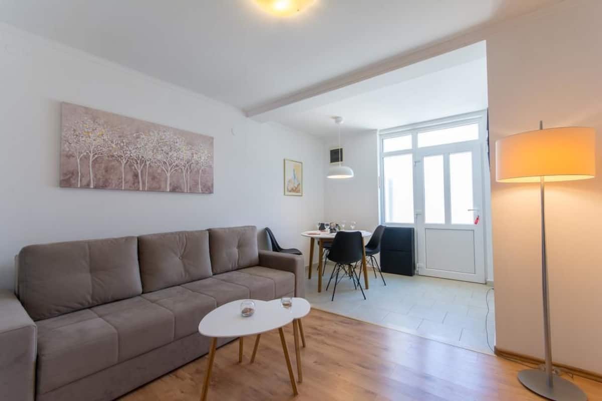 Un salon moderne avec un canapé, une petite table et un coin repas avec des chaises.
