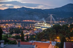 Une vue urbaine mettant en valeur un pont à haubans imposant, une rivière et un paysage montagneux en arrière-plan.