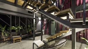 A modern outdoor seating area with wooden benches and a black chair, surrounded by potted plants and a staircase with wooden steps. - Top Sunlight Inn (Liuqiu)