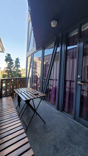 Um edifício moderno com grandes janelas de vidro, um deck de madeira e uma mesa de metal.