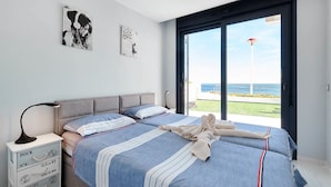 A modern bedroom with two beds, a large window with a view of the sea, and nautical-themed decor. - Dream Infinity View Apartment (Elche)
