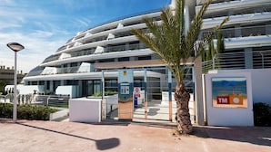 A modern building with a curved facade, multiple balconies, and a palm tree in the foreground. - Dream Infinity View Apartment (Elche)
