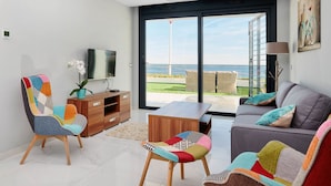 A modern living room with a large sliding glass door leading to a balcony with a view of the sea. - Dream Infinity View Apartment (Elche)