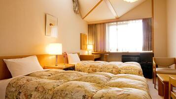 A hotel room with two beds, a desk, a chair, a TV, and a window with curtains.