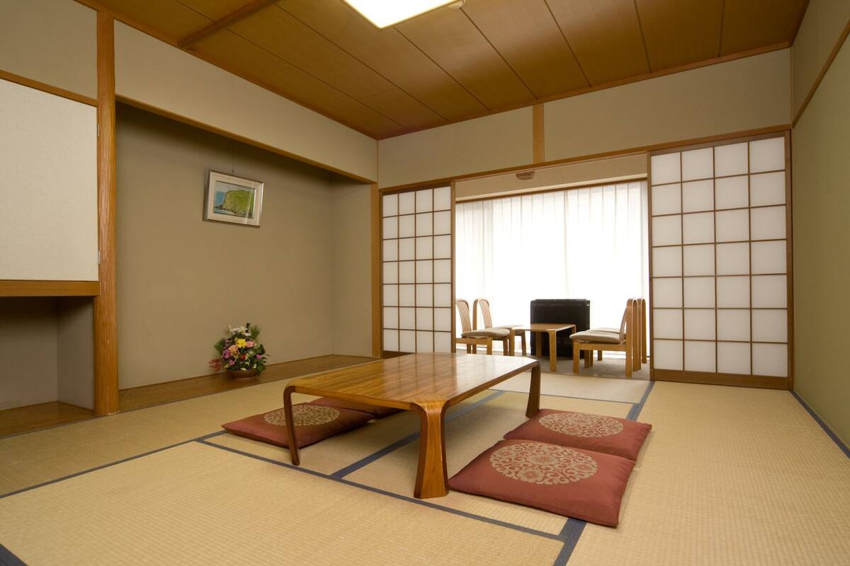 Een traditionele Japanse kamer met tatami vloerbedekking, een lage houten tafel en shoji schermen.